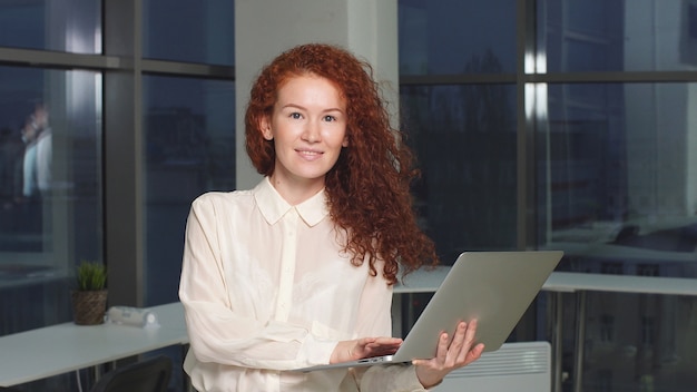 Ritratto delle free lance moderne della donna con il computer portatile in mani