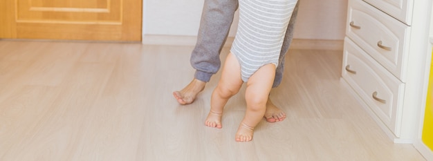 Ritratto delle gambe del bambino e della madre. Primi passi.