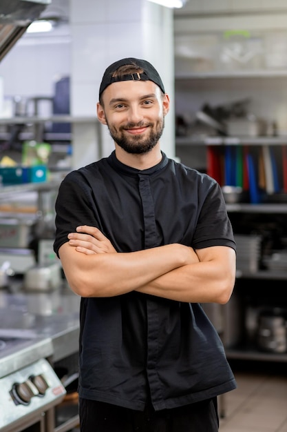 Ritratto dello chef del ristorante sorridente professionista in piedi sullo sfondo della cucina