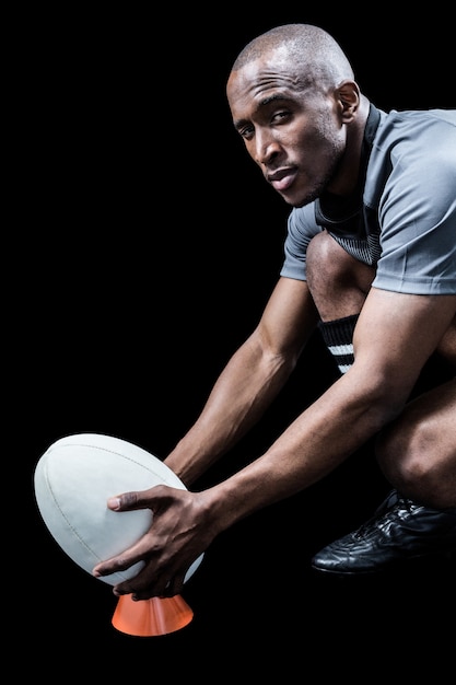 Ritratto dello sportivo che tiene la palla di rugby sul calcio del T