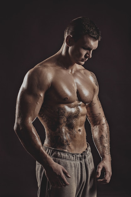 Ritratto dello studio di un maschio tatuato atletico senza camicia