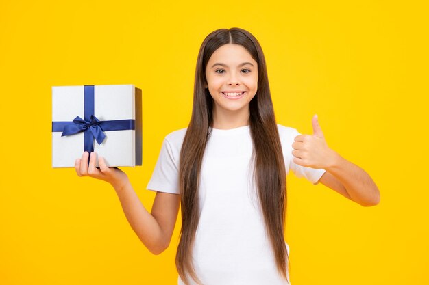 Ritratto di adolescente felice Ragazza sorridente in t-shirt Bambino adolescente azienda confezione regalo su sfondo giallo isolato Regalo per il compleanno dei bambini Vacanze estive