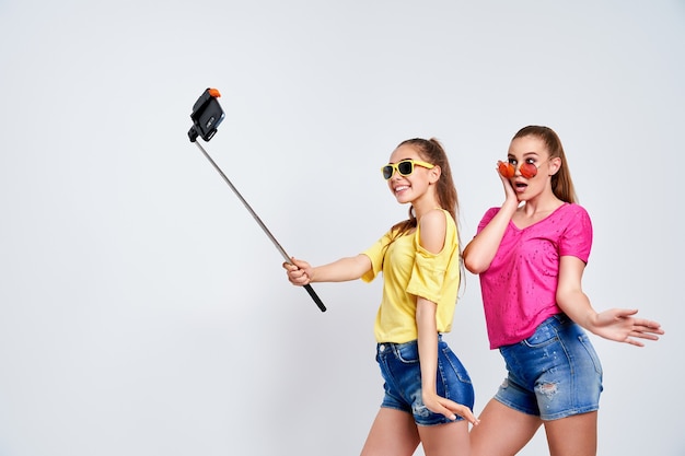 Ritratto di adolescenti felici prendendo selfie insieme isolato su whiteportrait di adolescenti felici in abiti estivi occhiali da sole prendendo selfie insieme isolato su bianco
