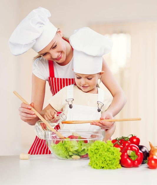 Ritratto di adorabile bambina e sua madre che cucinano insieme