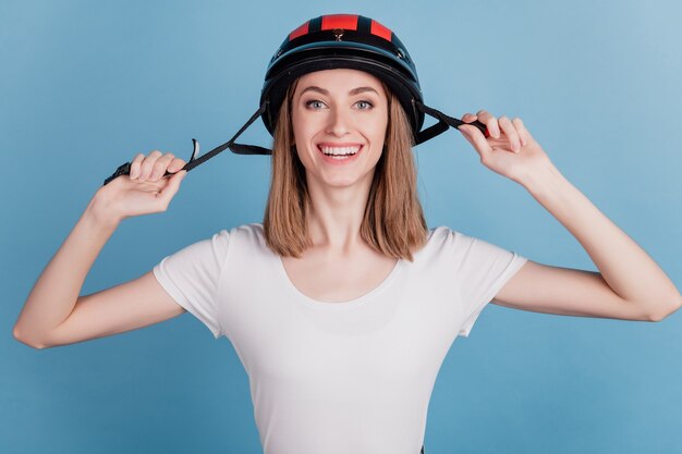 Ritratto di affascinante adorabile signora sicura di indossare un casco da motociclista sportivo su sfondo blu