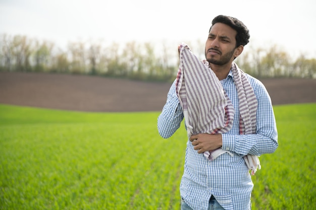 Ritratto di agricoltore in piedi in un campo di grano l'agricoltore si trova nel campo di grano verde guarda esamina il suo raccolto