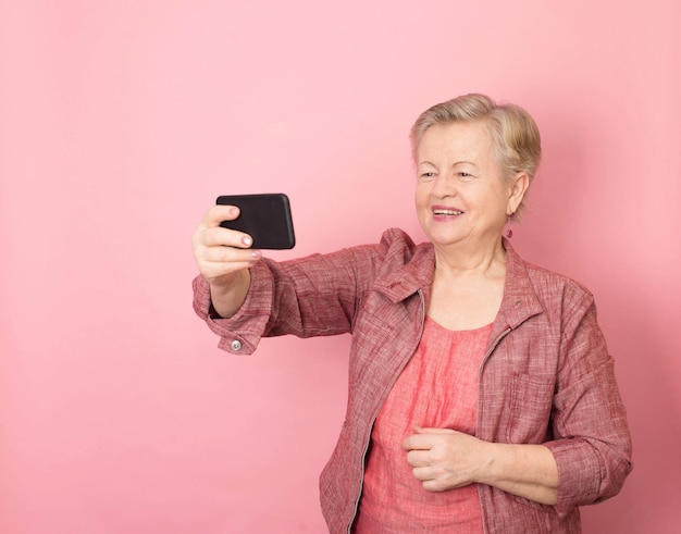 Ritratto di allegra donna bionda dai capelli grigi senior anni '70 che fa selfie girato sul cellulare