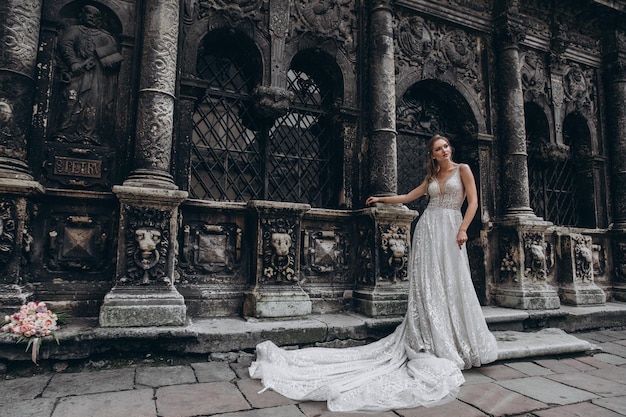 Ritratto di alta moda di giovane donna elegante all'aperto Sposa in abito bianco vicino al vecchio edificio