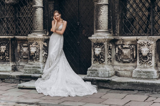 Ritratto di alta moda di giovane donna elegante all'aperto Sposa in abito bianco vicino al vecchio edificio