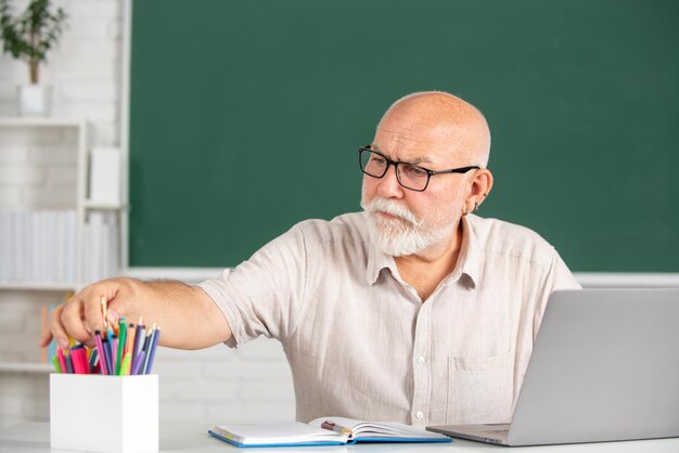 Ritratto di apprendimento degli adulti di insegnante maturo o professore tutor che lavora a tavola al college o al liceo