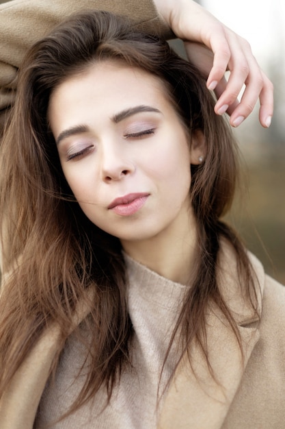 Ritratto di arte del primo piano di bellezza della donna in cappotto, modello di moda con cosmetici naturali della pelle pulita e trucco