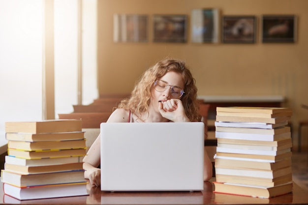 Ritratto di assonnato duro lavoro seduto in biblioteca