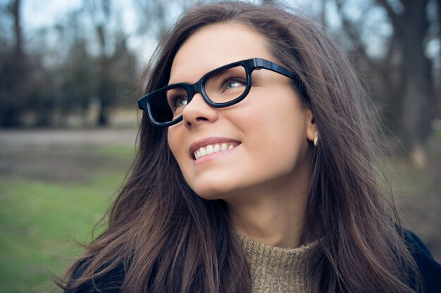 Ritratto di attraente giovane donna sorridente con lunghi capelli castani nel parco