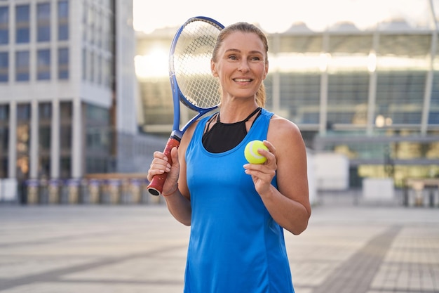 Ritratto di attraente tennista professionista di mezza età sportiva in possesso di racchetta da tennis e