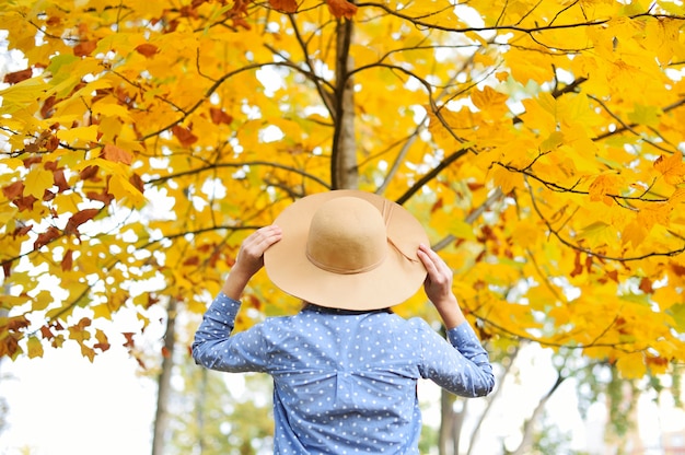 Ritratto di autunno della donna con il cappello all'aperto. Vista posteriore