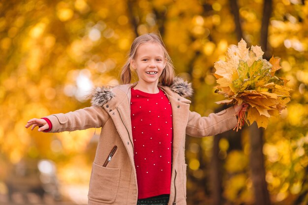 Ritratto di bambina adorabile con bouquet di foglie gialle in autunno