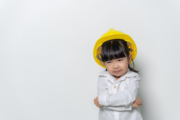 Ritratto di bambina asiatica carina in uniforme da ingegnere e casco su sfondo bianco