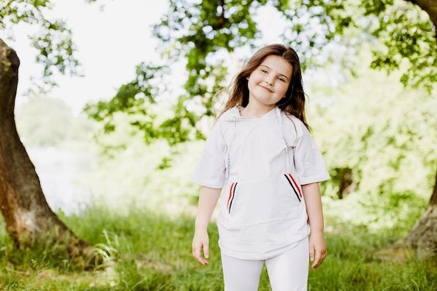 Ritratto di bambina carina in abiti sportivi nel parco estivo verde