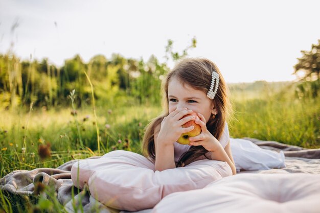 Ritratto di bambina che mangia mela rossa all'aperto