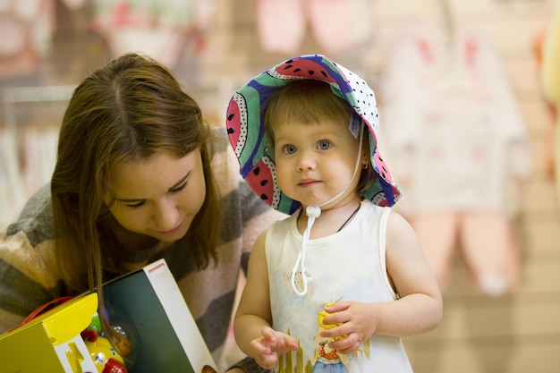 Ritratto di bambina con il cappello con sua madre al negozio per bambini