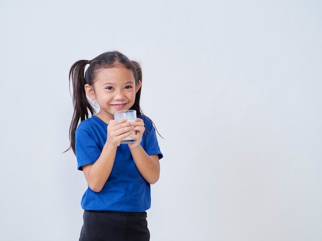 Ritratto di bambina felice con un bicchiere di latte sulla luce