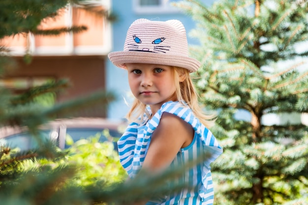 Ritratto di bambina felice di 4 anni in cappello estivo nel parco estivo all'aperto guardando la fotocamera