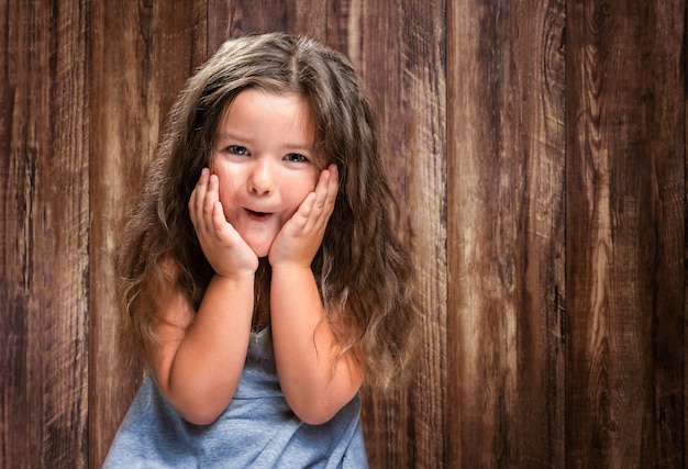 Ritratto di bambina felice sorpresa su fondo in legno