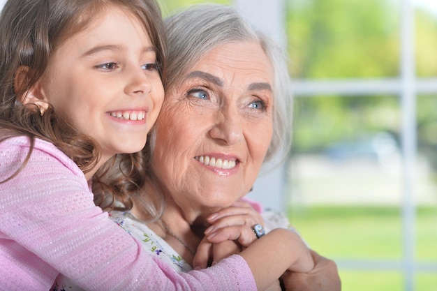 Ritratto di bambina graziosa che abbraccia sua nonna