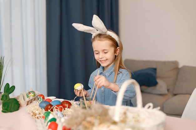 Ritratto di bambina in piedi nella moderna cucina leggera con uova di Pasqua