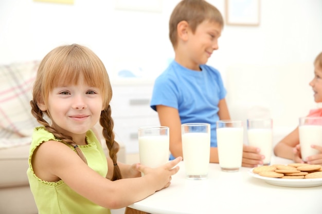 Ritratto di bambina seduta al tavolo con un bicchiere di latte