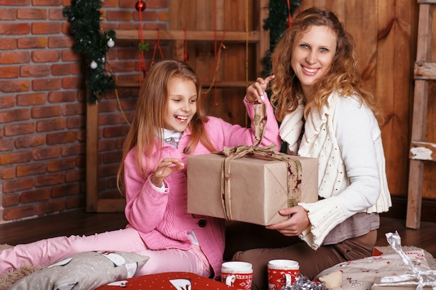 Ritratto di bambina sorridente felice con la madre seduta tra le decorazioni di Natale