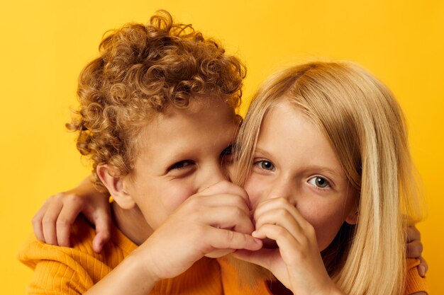 Ritratto di bambini carini che coccolano l'intrattenimento per l'infanzia di moda su sfondo colorato