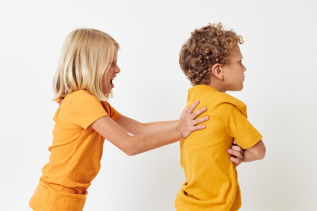 Ritratto di bambini carini in magliette gialle in piedi fianco a fianco emozioni infantili inalterate