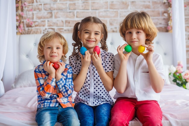 Ritratto di bambini di Pasqua, emozioni divertenti, sorpresa. I bambini, una ragazza e due ragazzi tengono in mano le uova di Pasqua. Foto divertente. Adorabile bambino in abiti colorati che si gode le vacanze