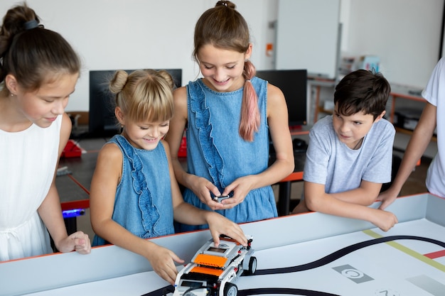 Ritratto di bambini felici a scuola in ufficio a una lezione di robotica, con un ufficio moderno con computer