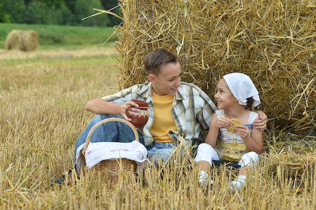 Ritratto di bambini felici con latte e frittelle in campo all'estate