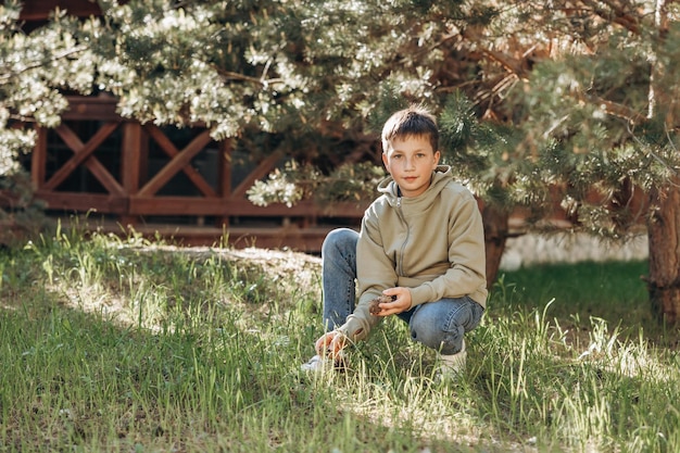 Ritratto di bambino che raccoglie e tiene coni di pino nella foresta Ragazzo adolescente che si gode la natura camminando nel parco in una giornata estiva Concetto di viaggio locale