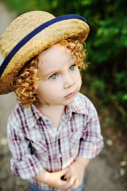 Ritratto di bambino dai capelli rossi ricci in un cappello.