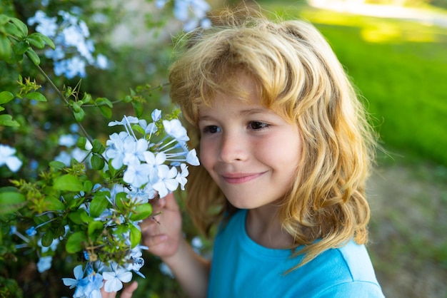 Ritratto di bambino piccolo all'aperto sul prato piccolo bambino carino con fiori in un giardino i bambini giocano ou