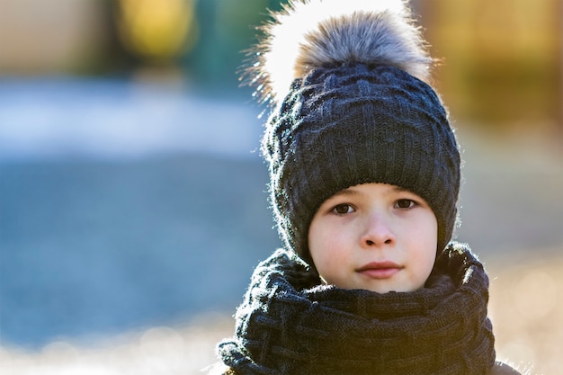 Ritratto di bambino ragazzo in cappello e sciarpa all'aperto nella soleggiata giornata invernale