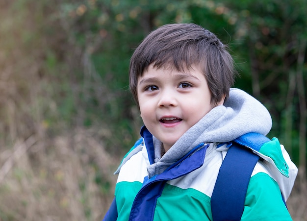 Ritratto di bambino sano guardando cameara con volto sorridente, un bambino felice che indossa panno caldo giocando fuori