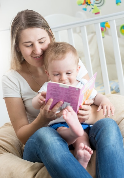 Ritratto di bambino seduto sulle ginocchia della madre e leggendo un libro