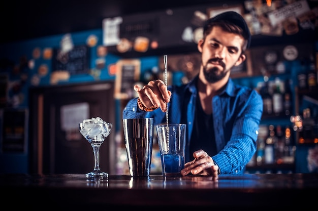 Ritratto di barista che versa una bevanda alcolica fresca nei bicchieri mentre si trova vicino al bancone del bar