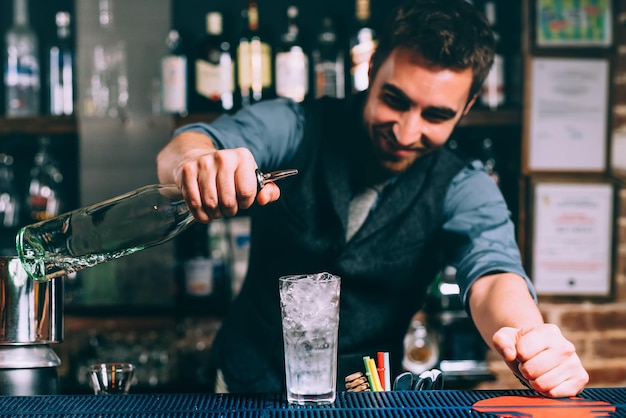 Ritratto di barman e dettagli ravvicinati della preparazione di bevande alcoliche e cocktail