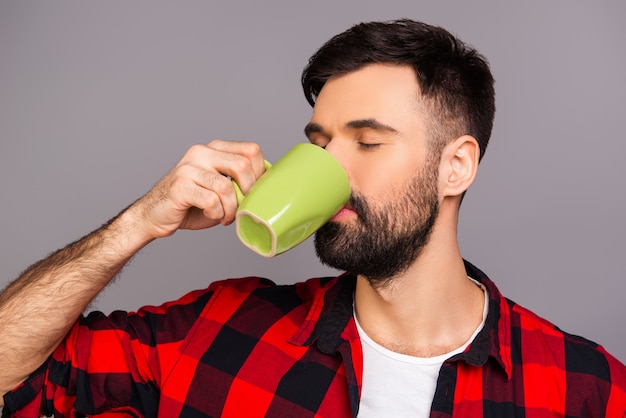 Ritratto di bel giovane uomo barbuto che beve caffè