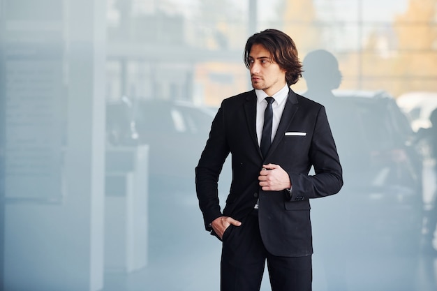 Ritratto di bel giovane uomo d'affari in abito nero e cravatta.