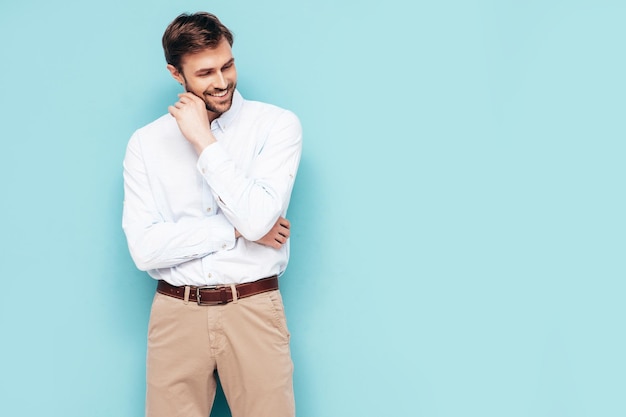 Ritratto di bel modello sorridente Uomo alla moda sexy vestito in camicia e pantaloni Moda uomo hipster in posa vicino al muro blu in studio isolato