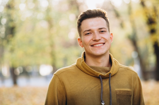 Ritratto di bel ragazzo sorridente nel parco in autunno