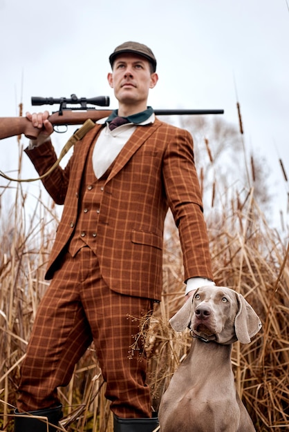 Ritratto di bel ragazzo vestito con cane grigio a caccia, guardando a lato. vista in basso