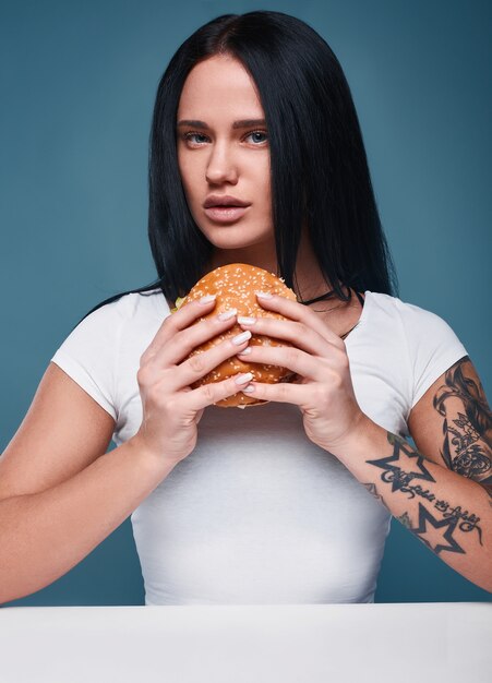 Ritratto di bella affascinante tatuaggio ragazza con hamburger